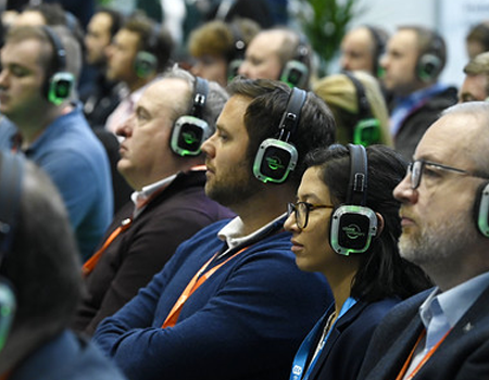 Directivos siguiendo una ponencia con auriculares inalámbricos