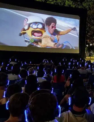 Cine al aire libre con público usando auriculares inalámbricos