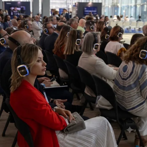 Público de conferencia siguiendo la ponencia con auriculares