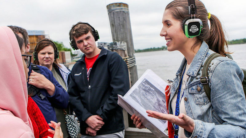 Guía turística explicando a un grupo con auriculares inalámbricos